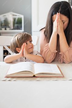 a woman and child sitting at a table with an open book in front of them