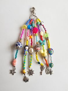 a multicolored beaded necklace with charms hanging from it's side on a white surface