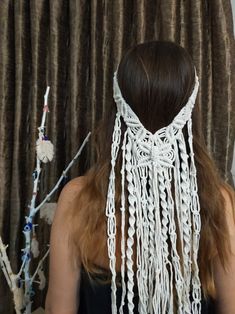 a woman with long brown hair wearing a white crochet head piece and beads