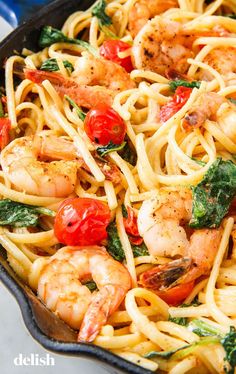 pasta with shrimp, tomatoes and spinach in a skillet