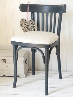 a wooden chair with a white cushion on it's seat next to a chest