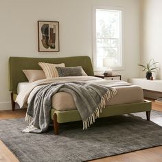 a bed sitting on top of a wooden floor next to a window