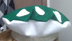 a green and white mushroom hat sitting on top of a mannequin's head