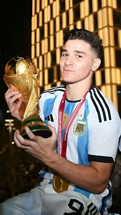 a young man holding a soccer ball and trophy