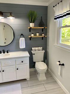 a white toilet sitting in a bathroom next to a sink under a large round mirror