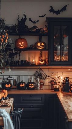 a kitchen decorated for halloween with pumpkins, candles and other decorations on the shelves