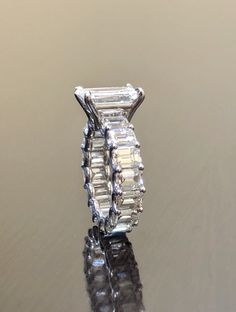 an engagement ring with three baguetts on the side, sitting on top of a reflective surface