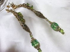 Hand made, these Antique emerald green and lime faceted crystal beads are just sparkling with carnival color! They are beautifully paired with these vintage brass filigree elongated beads that I have set with gemstones of various colors. They are dangling from 14 k gf post earrings with triangular post push backs. They are approx. 2 and 3/4 inches long. Pretty earrings  for a green eyed gal! Gift wrapped year round! Green Dangling Bead Chandelier Earrings, Green Jeweled Crystal Drop Earrings, Green Czech Glass Jewelry With Dangling Beads, Elegant Green Beaded Crystal Earrings, Green Dangling Beads Earrings For Wedding, Green Jeweled Chandelier Earrings For Wedding, Elegant Green Czech Glass Earrings, Green Dangle Jewelry With Faceted Beads, Green Crystal Drop Earrings With Dangling Beads