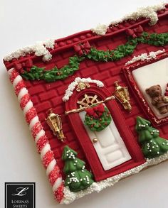 a red and white christmas themed cake with teddy bears in the front door decorated for christmas