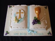 a cake decorated to look like an open book with grapes and a cross on it