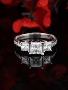 three stone diamond ring with red and white diamonds on the side, surrounded by flowers