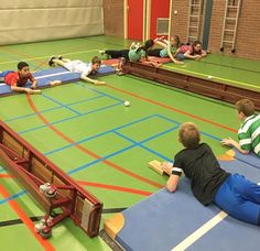 several children are laying on the floor in a gym and one boy is playing with a ball