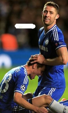 two soccer players are hugging each other in the middle of a field with an ad above them