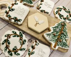 decorated cookies are arranged on a wooden platter with holly and pine tree decorations, along with the names of their guests