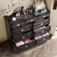 a black dresser with drawers and pictures on the wall