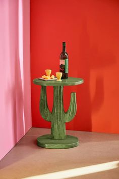 a small table with a bottle of wine on it next to a cactus shaped table