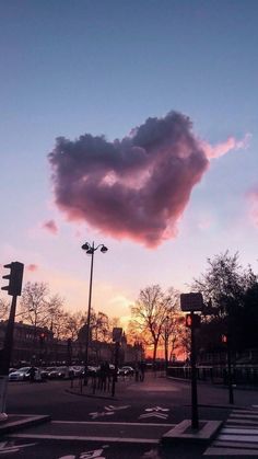 a pink cloud in the sky over a city street