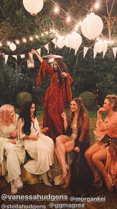 a group of women sitting next to each other on top of a grass covered field