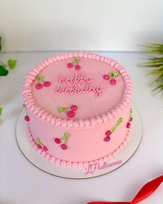 a pink birthday cake sitting on top of a table