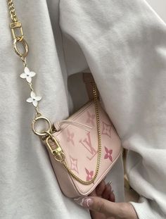 a woman holding onto a pink purse with gold chains on her neck and white shirt behind her