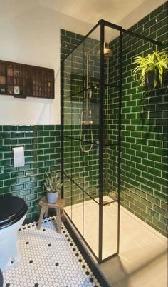 a black and white tiled bathroom with green tiles on the walls, toilet and shower stall