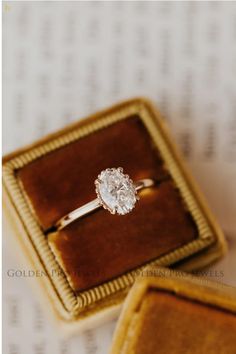 an engagement ring sitting in a box on top of a piece of paper next to it