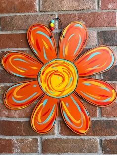 an orange and blue flower on a brick wall with beads hanging from it's center