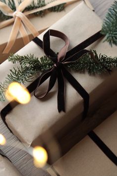 two wrapped presents with ribbons and lights on the top one is tied in brown ribbon