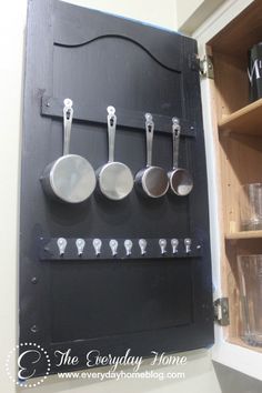 there are many pots and pans hanging on the wall with spoons in them