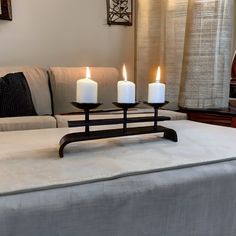 three lit candles sit on top of a couch