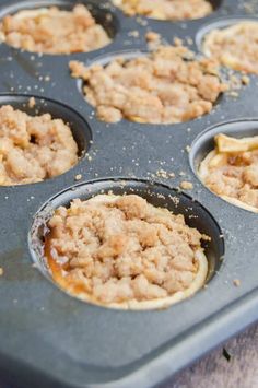 an uncooked muffin tin filled with cupcakes covered in crumbs