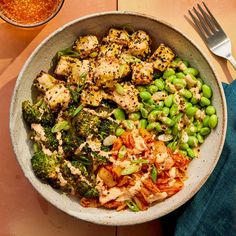 a bowl filled with chicken, broccoli and peas