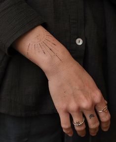 a person's hand with a small tattoo on their left wrist and the other arm