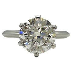 an engagement ring with a round brilliant cut diamond in the center, on a white background