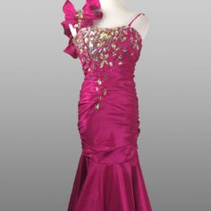 a pink evening gown with gold sequins and bows on the shoulder, in front of a gray background