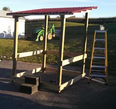 there is a small wooden structure that has two tractors on it and some steps leading up to the roof