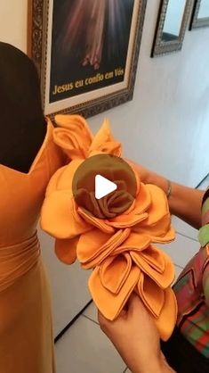 a woman is holding up a flower made out of fabric and cloth material in front of a mannequin's head