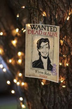 a wanted dead or alive sign hanging from a tree with lights on it's branches