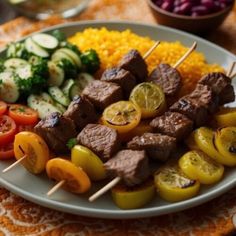 a white plate topped with meat and veggies on skewers next to rice