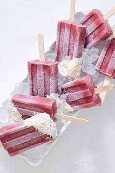 four popsicles with coconut on them are sitting on an ice - cream platter