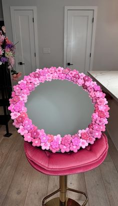 a mirror with pink flowers on it sitting on a stool in front of a door