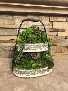 a three tiered planter filled with succulents and other greenery