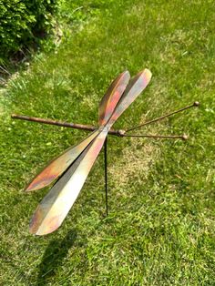 a metal dragonfly sitting on top of a lush green field