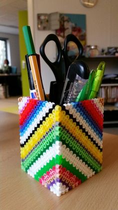 a colorful pencil holder with scissors, pens and other office supplies in it on a table