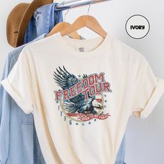 "Super comfy USA shirt with a retro design for The Fourth of July! Our '100% ring spun cotton' Comfort Colors tee and Color options are perfect for this Independence Day! ✨The Comfort Colors brand is highly regarded for the quality and longevity of materials they use for their products.  ✨This style of garment (Comfort Colors Tee 1717) is PIGMENT-DYED, so the colors and texture of the garment continue to soften and age after each wash, giving it a 'vintage' look, while still maintaining a high-q Retro Cotton Tops For 4th Of July, 4th Of July Fan Merchandise Cotton Tops, Retro Cotton Top For 4th Of July, Cotton Tops With Custom Print For 4th Of July, Cotton Tops For 4th Of July Fan Merchandise, 4th Of July Cotton Tops With Custom Print, Vintage Cotton Tops For 4th Of July, American Style Memorial Day T-shirt With Graphic Print, Patriotic 4th Of July T-shirt For Streetwear