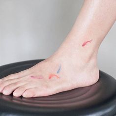 a person's foot on top of a black chair with red and blue ink