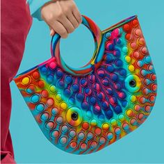 a woman holding a colorful handbag with circles on it's handle and handles