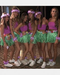 a group of young women standing next to each other wearing green and purple skirts with flowers in their hair