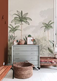 a room with palm trees on the wall and a wicker basket next to it