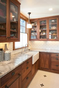 a large kitchen with wooden cabinets and marble counter tops, along with black and white tile flooring